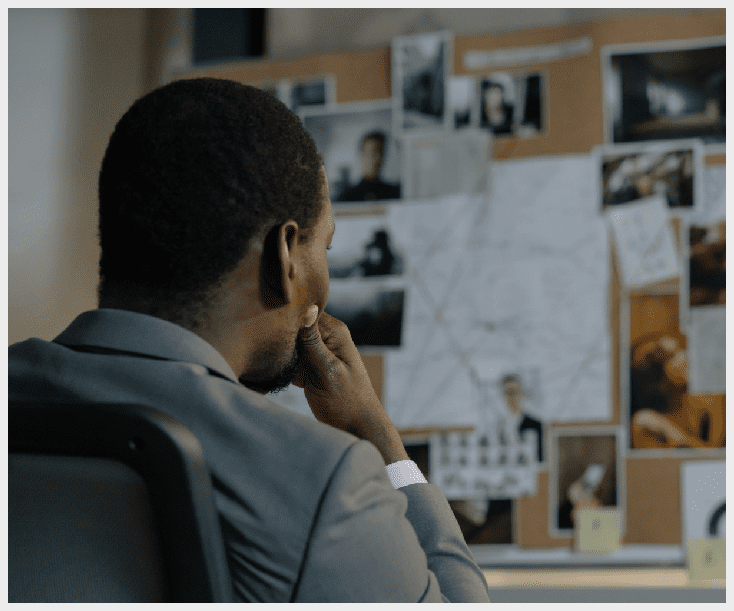 A man sitting in front of a wall with pictures on it.