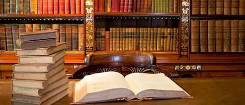 A book is open on the table in front of some books.